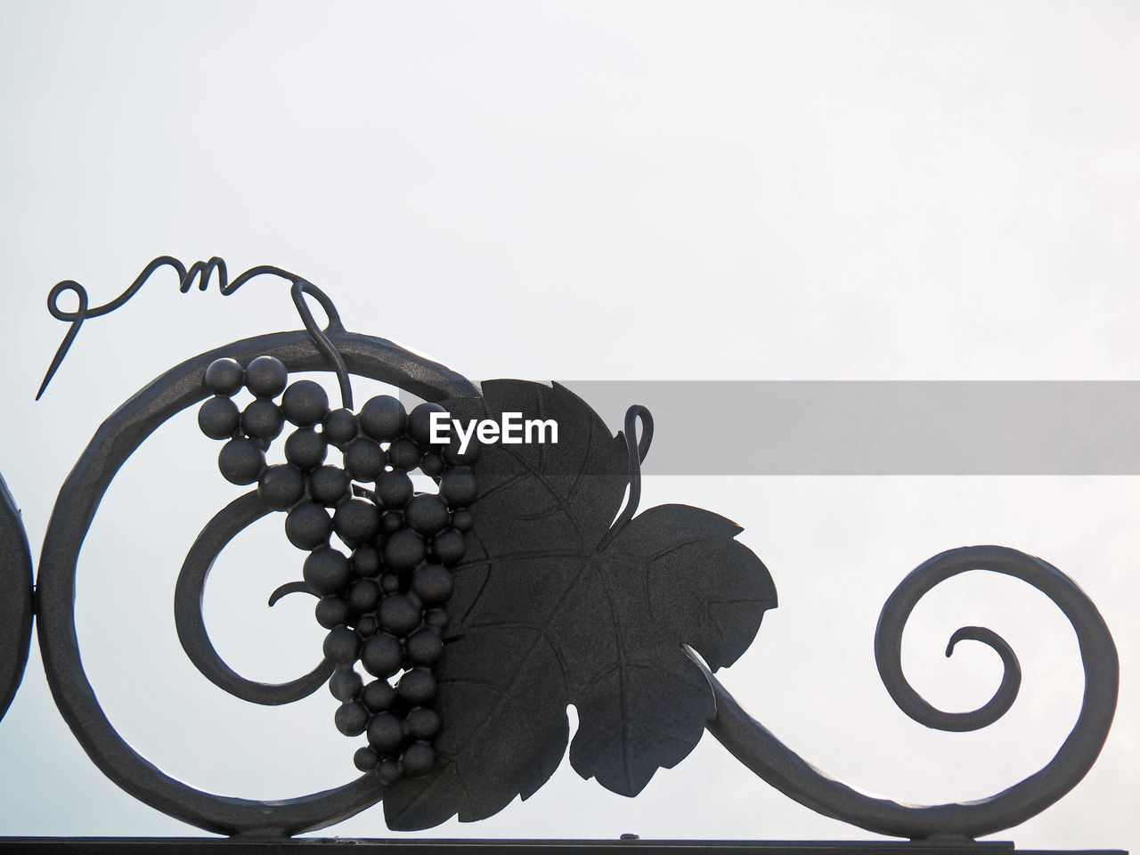 Low angle view of grape shape art on gate against clear sky
