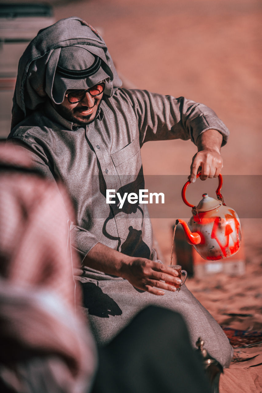 Man wearing traditional clothing pouring tea in cup