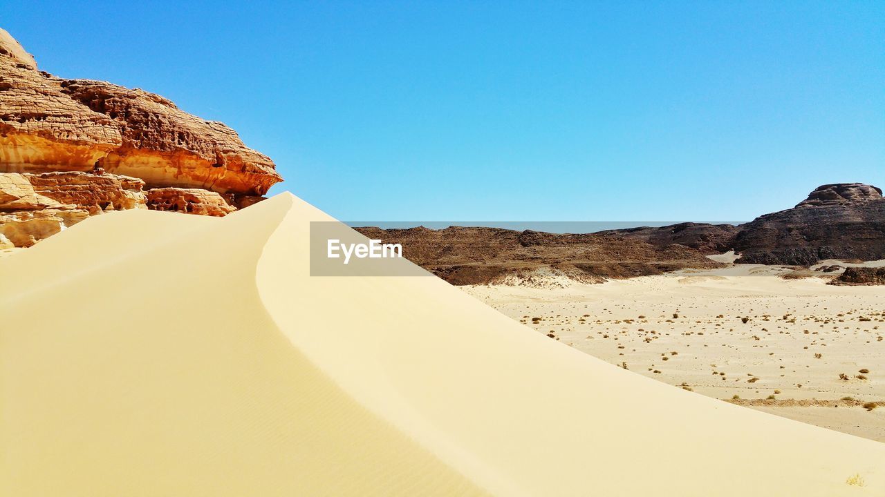 Scenic view of sand dune against clear sky