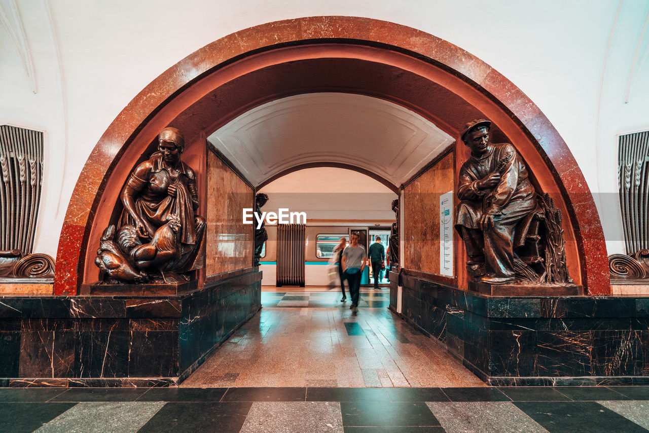 PEOPLE WALKING IN BUILDING SEEN THROUGH ARCHWAY