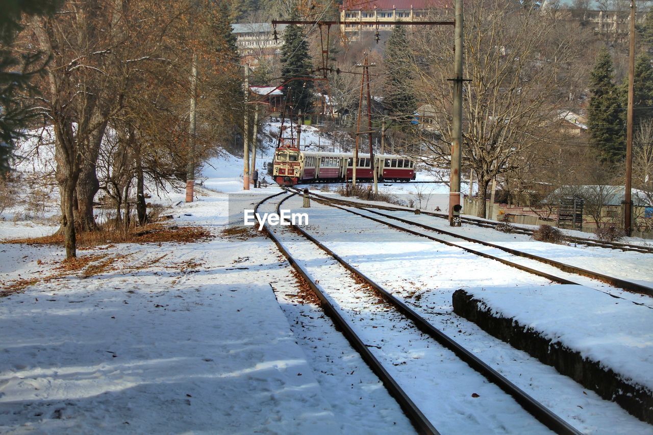 Snow covered railroad tracks by trees during winter