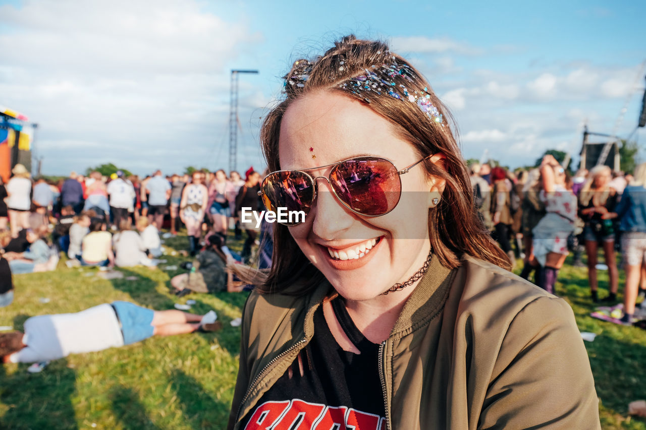 Portrait of smiling young woman wearing sunglasses in music festival