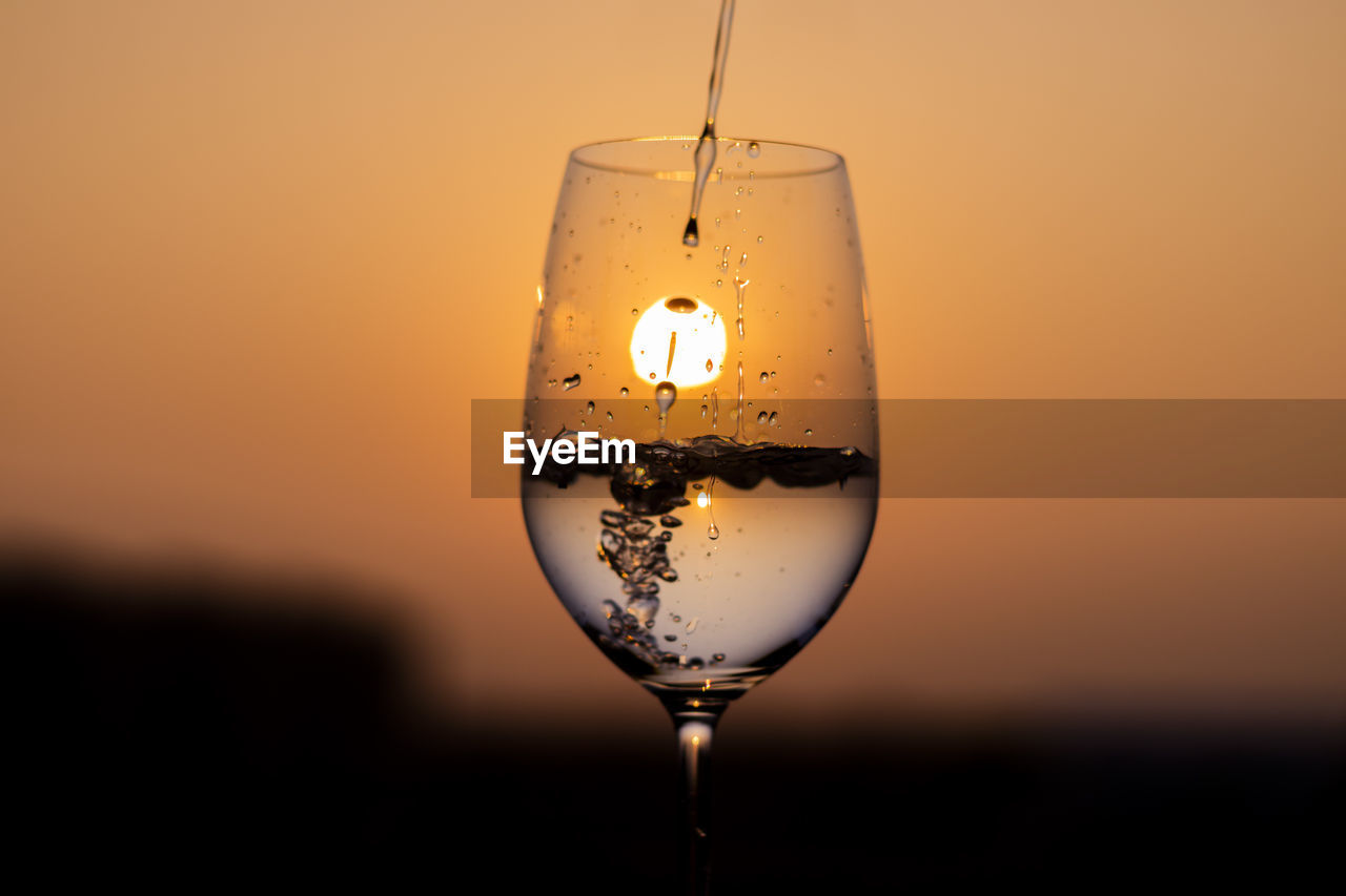 refreshment, glass, drink, alcohol, food and drink, sunset, drinking glass, household equipment, wine, water, wine glass, no people, nature, studio shot, alcoholic beverage, colored background, sky, reflection, close-up, freshness, transparent, yellow, single object, orange color, stemware, copy space, focus on foreground, champagne stemware, indoors, drop, bubble