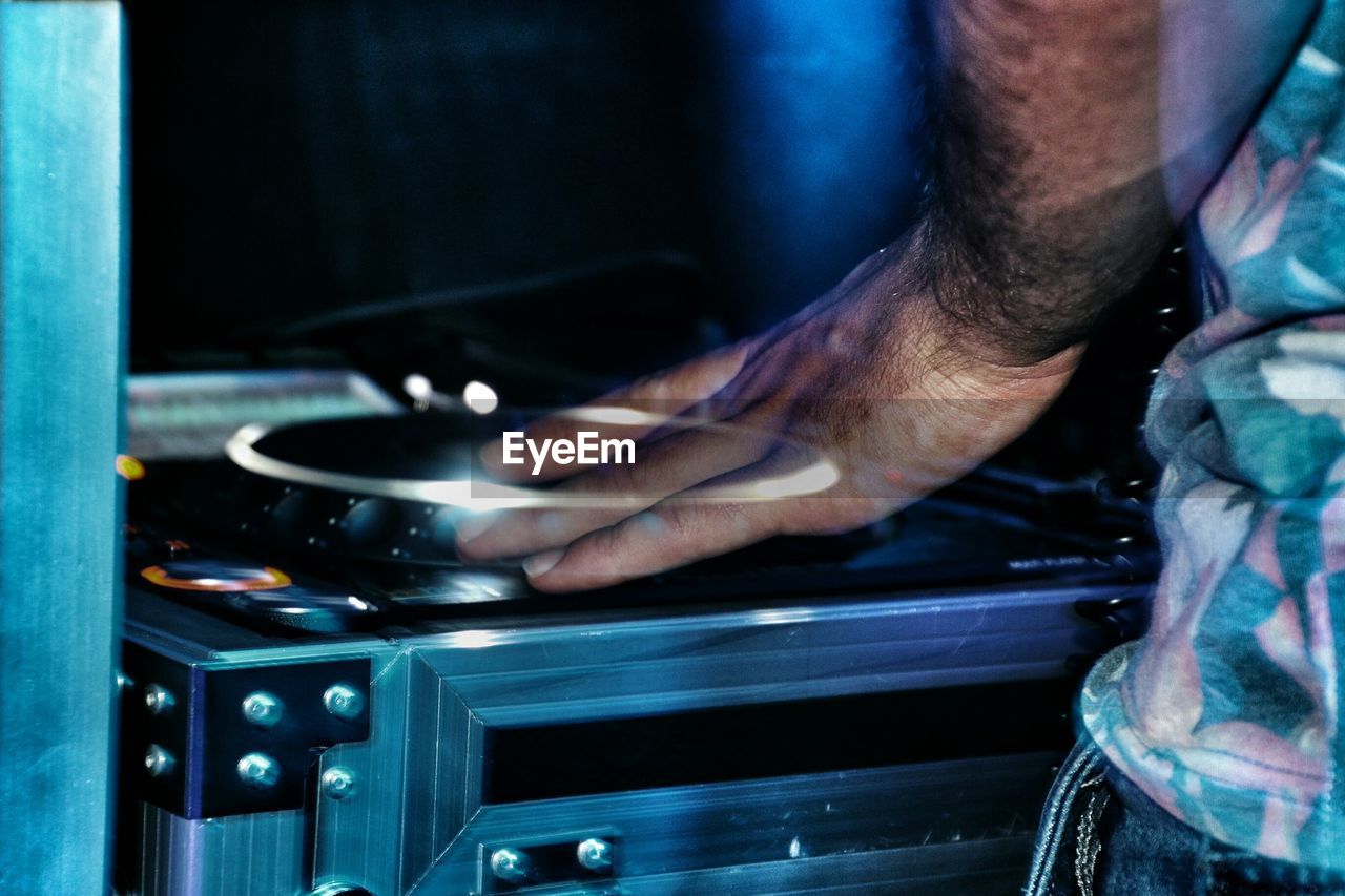 Cropped image of dj mixing records at turntables