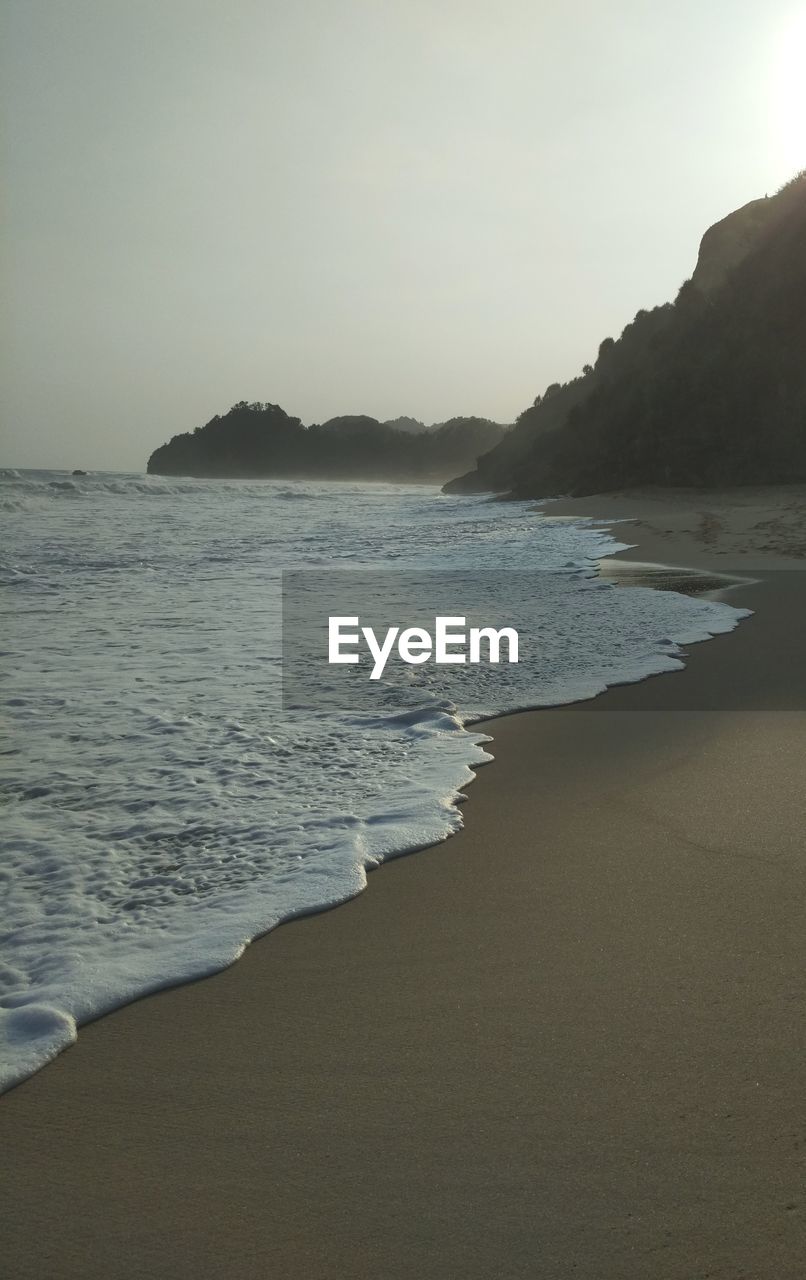 SCENIC VIEW OF BEACH AGAINST CLEAR SKY AT SUNSET