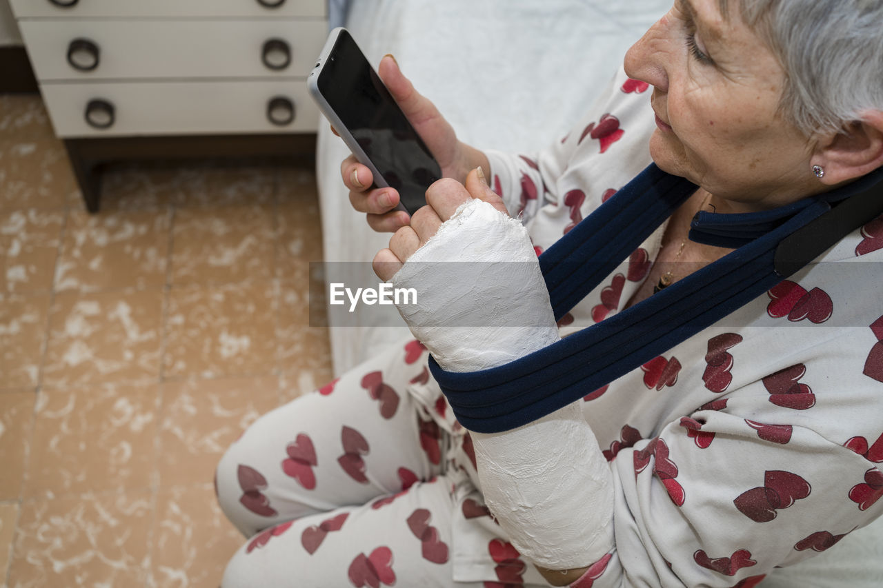 Caucasian senior woman with white hair with broken arm sitting