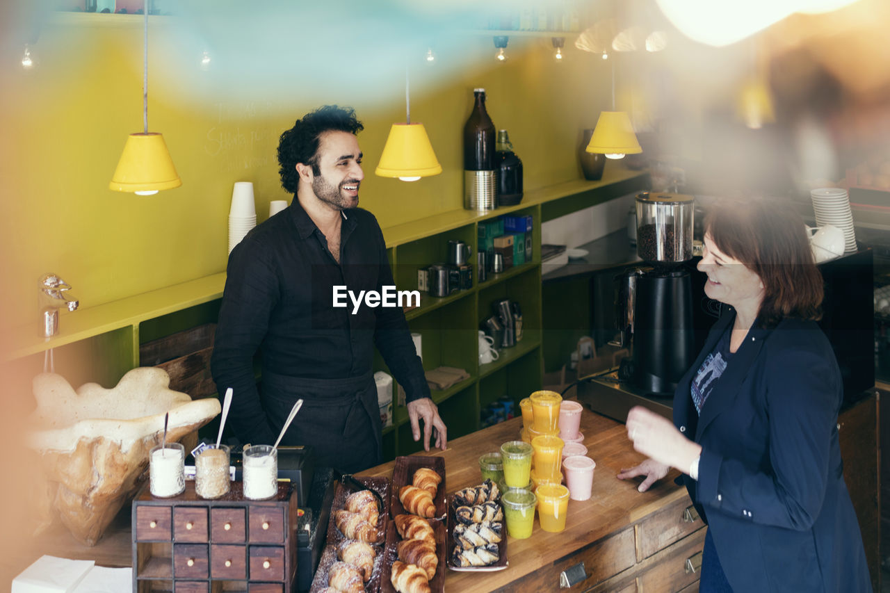 High angle view of happy customer and owner standing in coffee shop