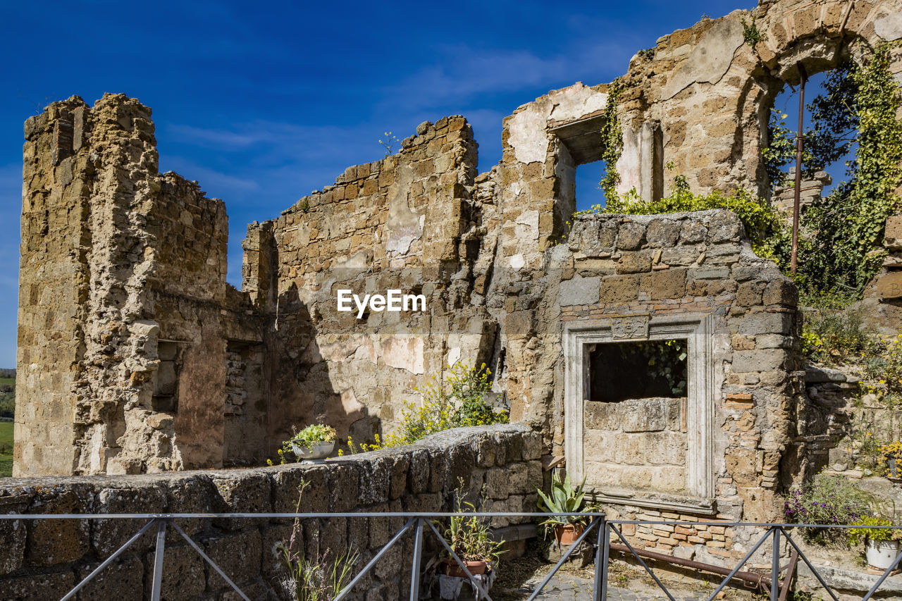 architecture, history, ruins, the past, built structure, old ruin, sky, ancient, building, travel destinations, ancient history, old, building exterior, nature, ruined, travel, damaged, abandoned, no people, tourism, wall, fortification, stone material, rundown, blue, ancient civilization, outdoors, day, plant, archaeology, weathered, village, clear sky, bad condition, historic site, archaeological site, wall - building feature, deterioration, decline, broken, castle, medieval