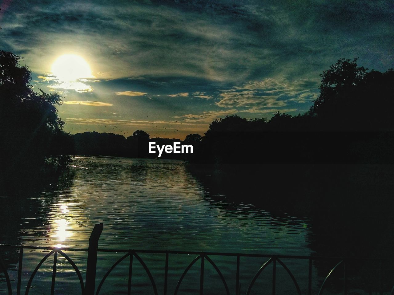 SILHOUETTE TREES BY LAKE AGAINST SKY AT SUNSET