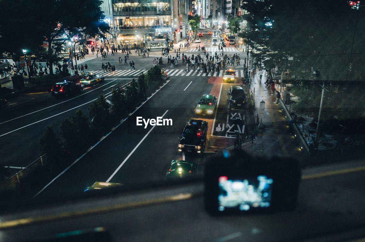 High angle view of street in illuminated city seen through window at night