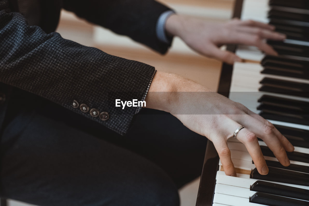 cropped hand of man playing piano