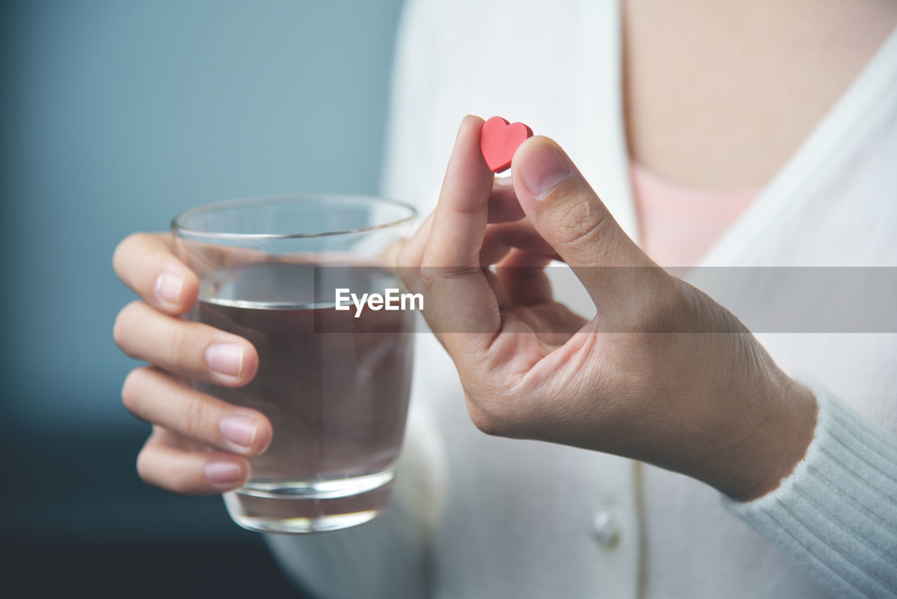 MIDSECTION OF WOMAN HOLDING DRINK