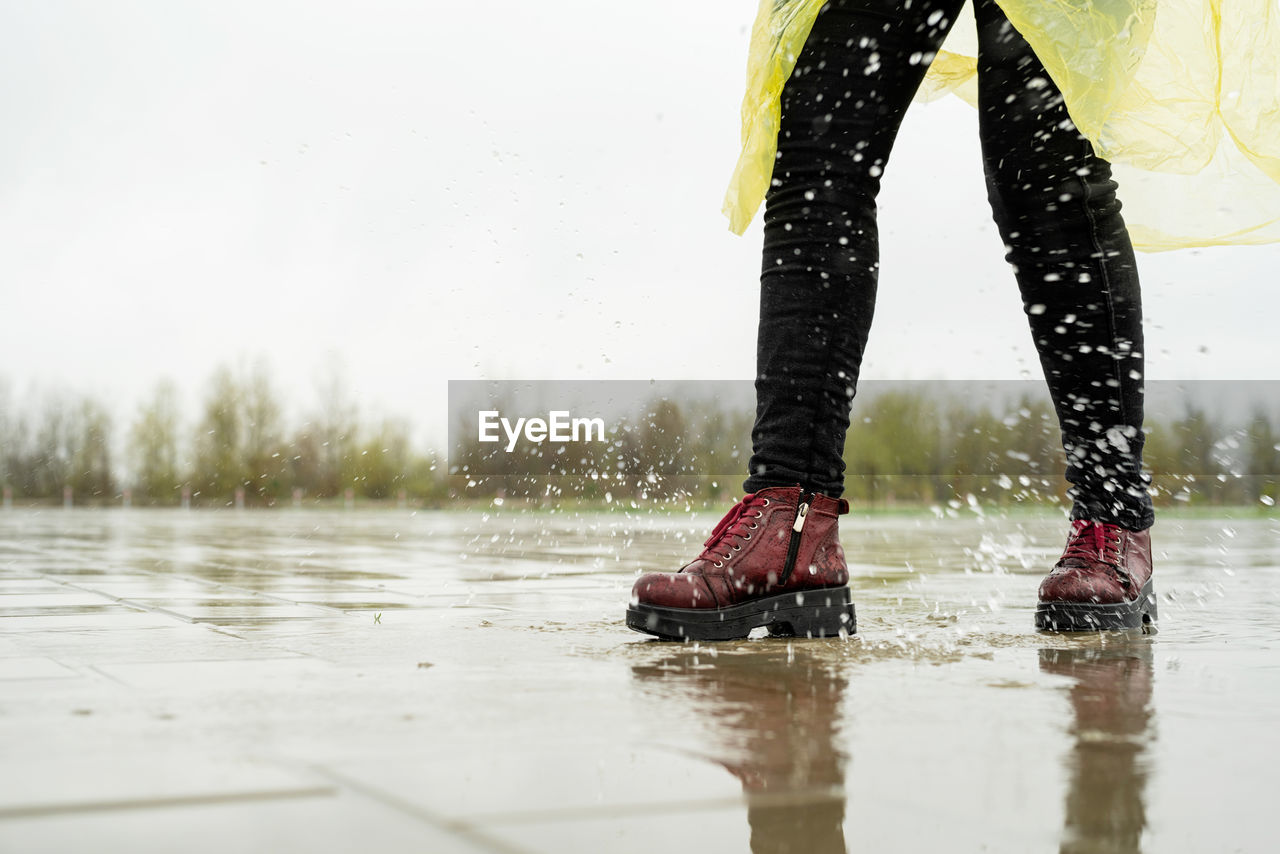 Low section of woman standing in water on footpath