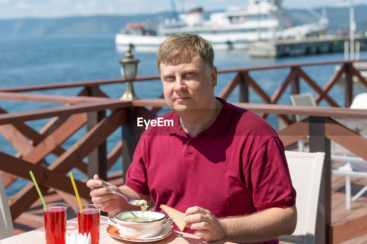 An adult blonde man has lunch on the beach in a cafe fresh air.