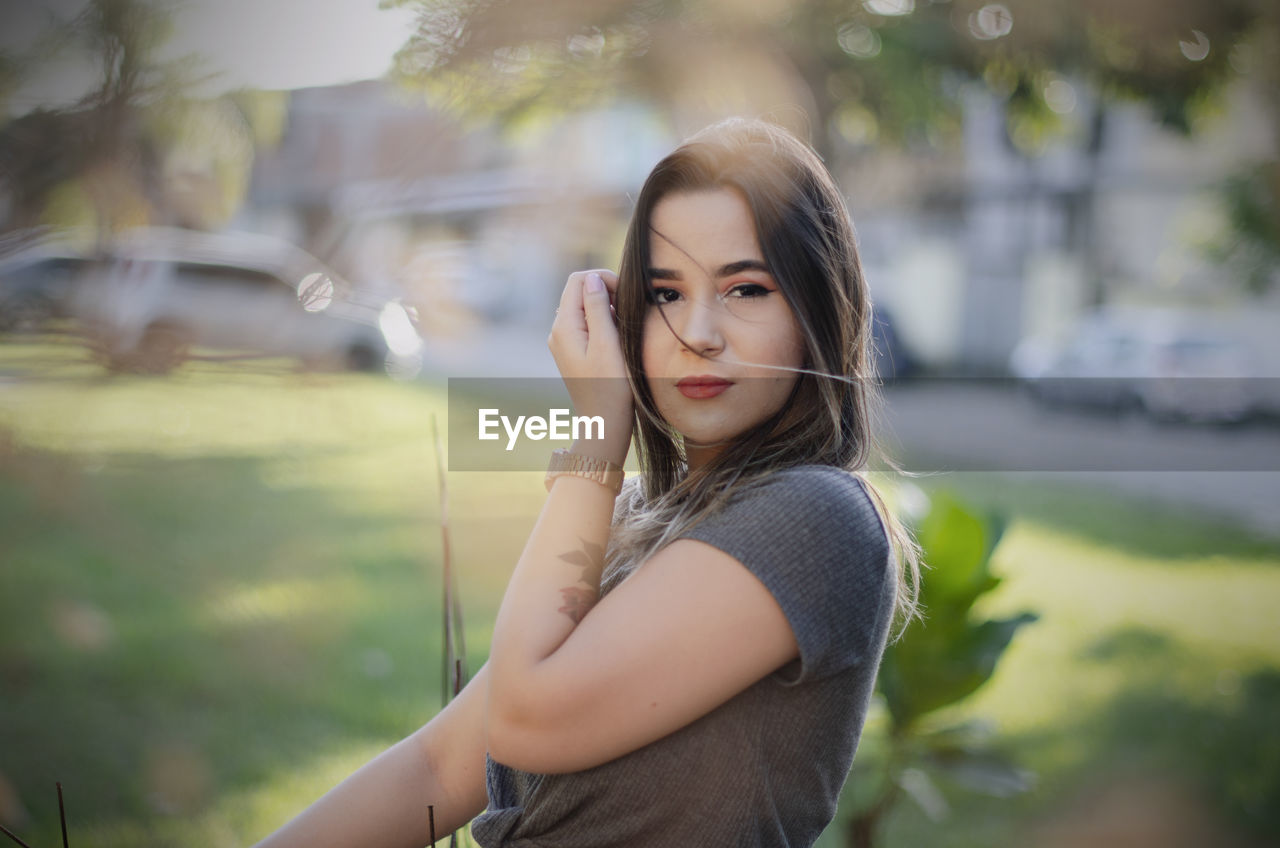 PORTRAIT OF YOUNG WOMAN STANDING OUTDOORS