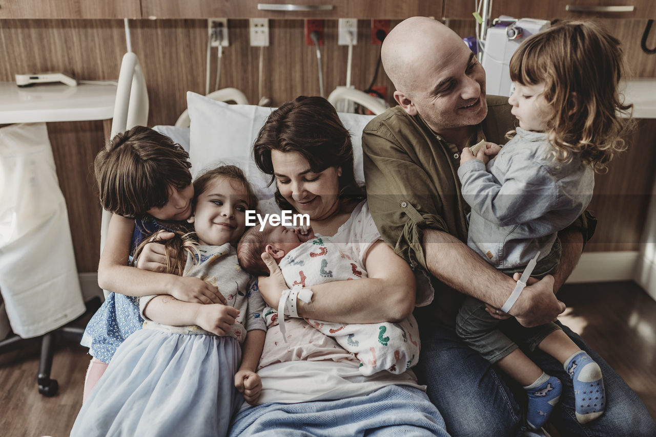 Mid view of whole family holding newborn son in hospital