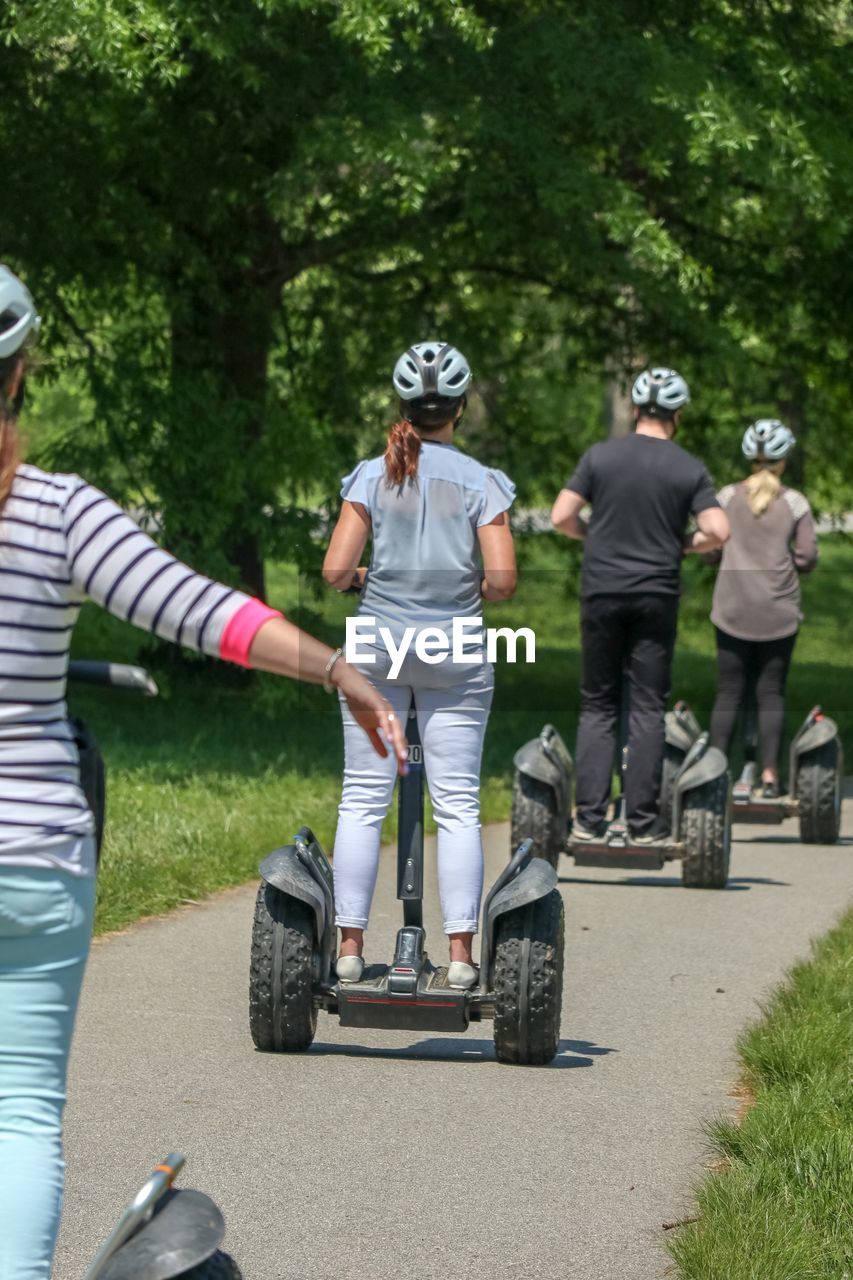 Rear view of people riding segway in park