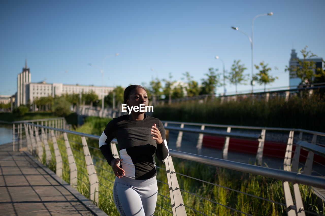 African american sportswoman running on embankment