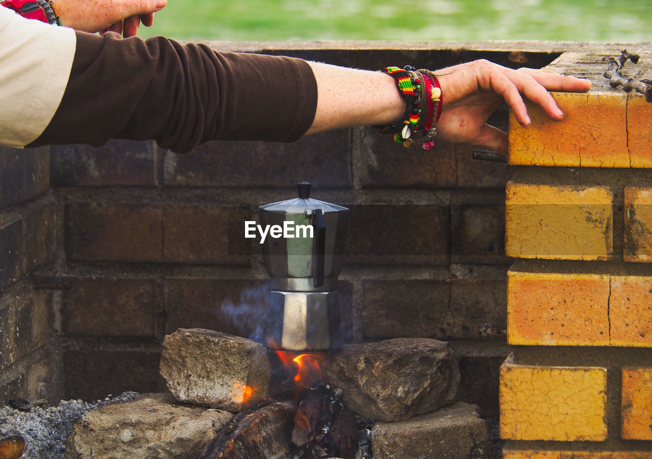 Cropped hands of person preparing food over fire