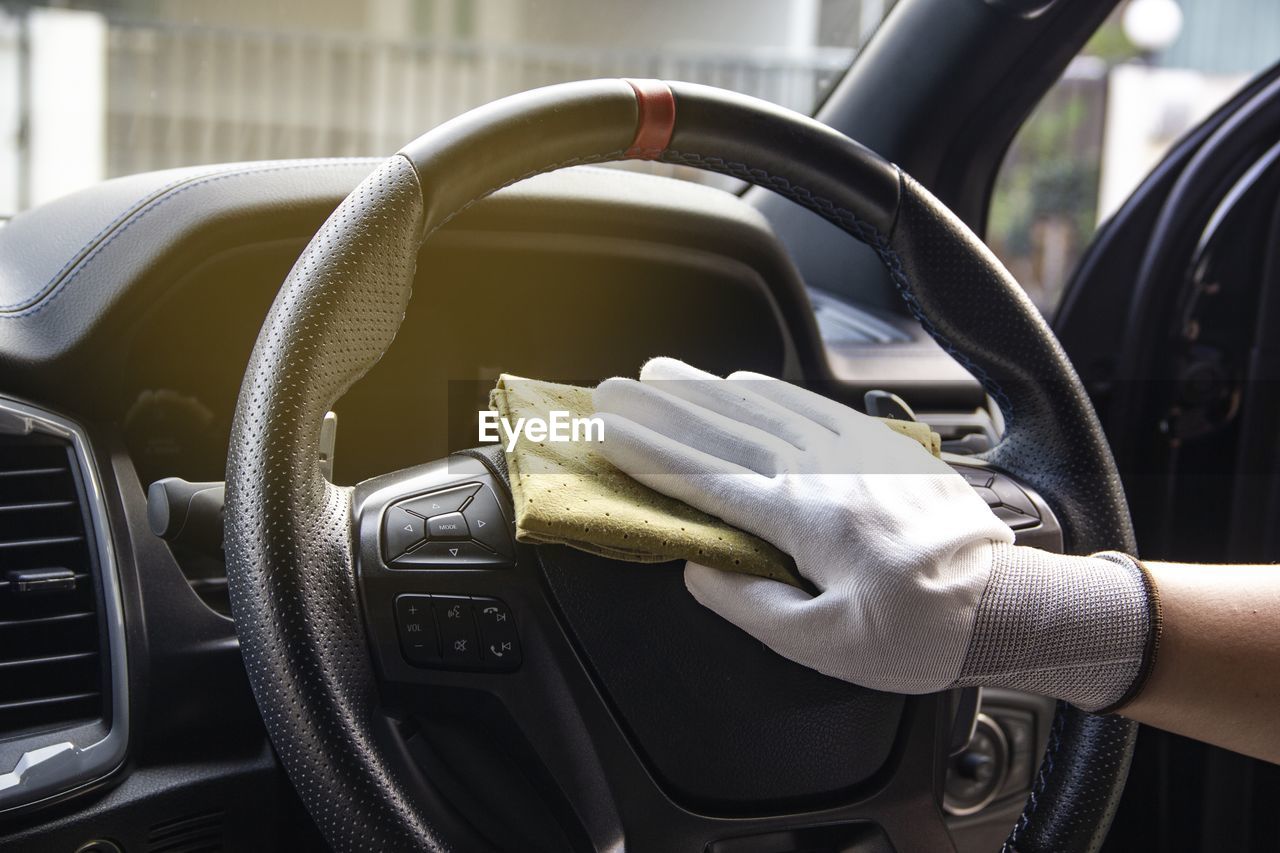 Close-up of hand cleaning steering wheel