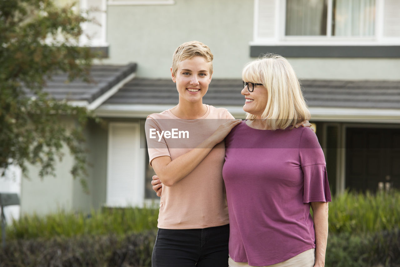 Portrait of smiling woman with mother in front of a house