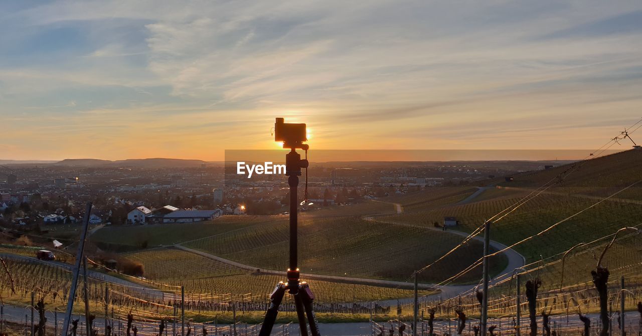 Camera on tripod against landscape during sunset