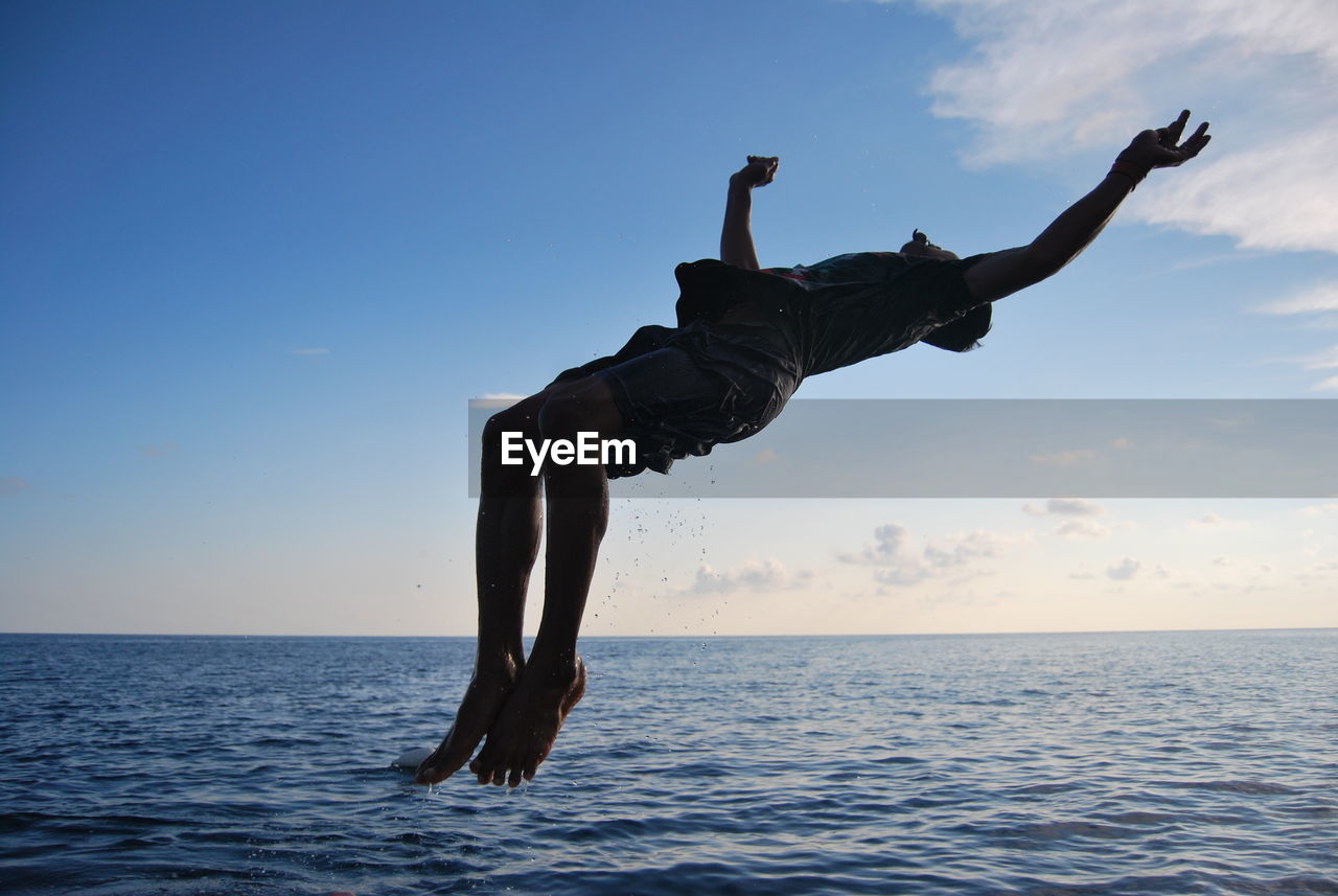 MAN JUMPING AT SEA AGAINST SKY