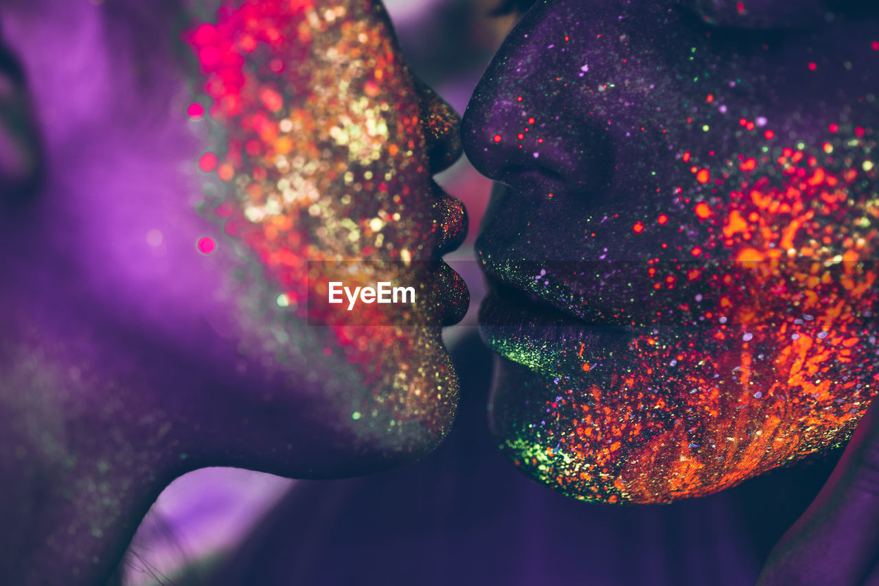 Close-up of couple with multi colored face paint kissing