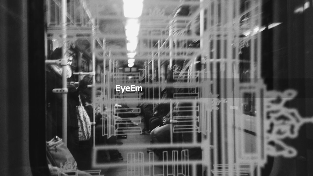 People in train seen through window glass