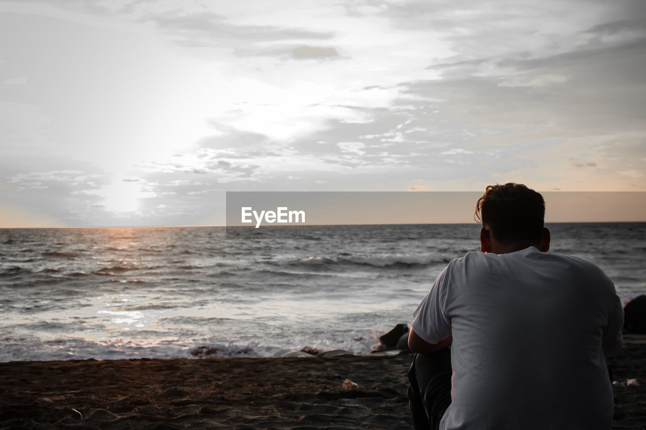 Rear view of man looking at sea against sky