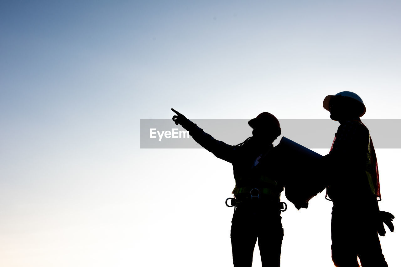 REAR VIEW OF SILHOUETTE FRIENDS STANDING AGAINST SKY