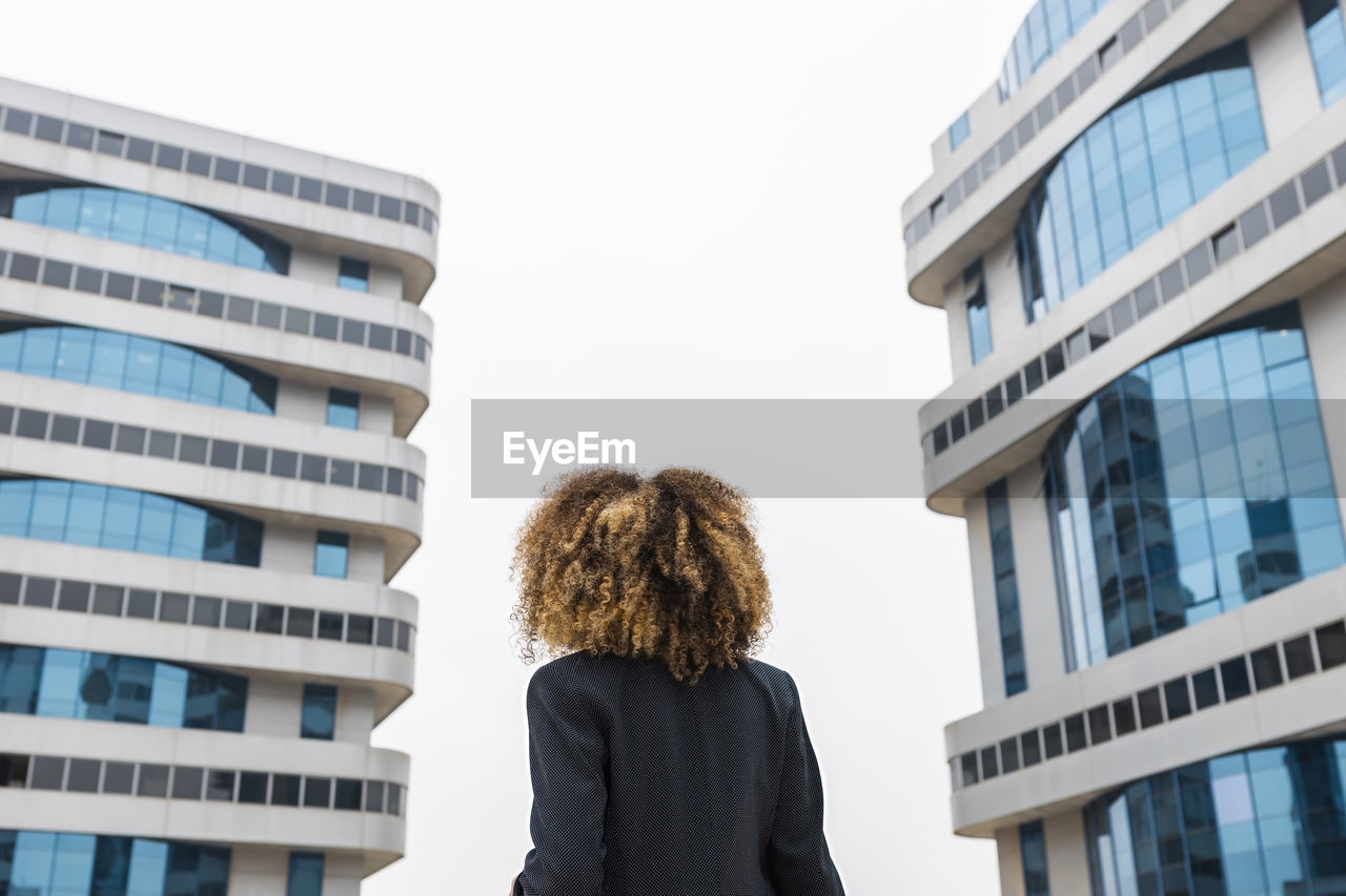 Afro businesswoman standing in front of office building in city