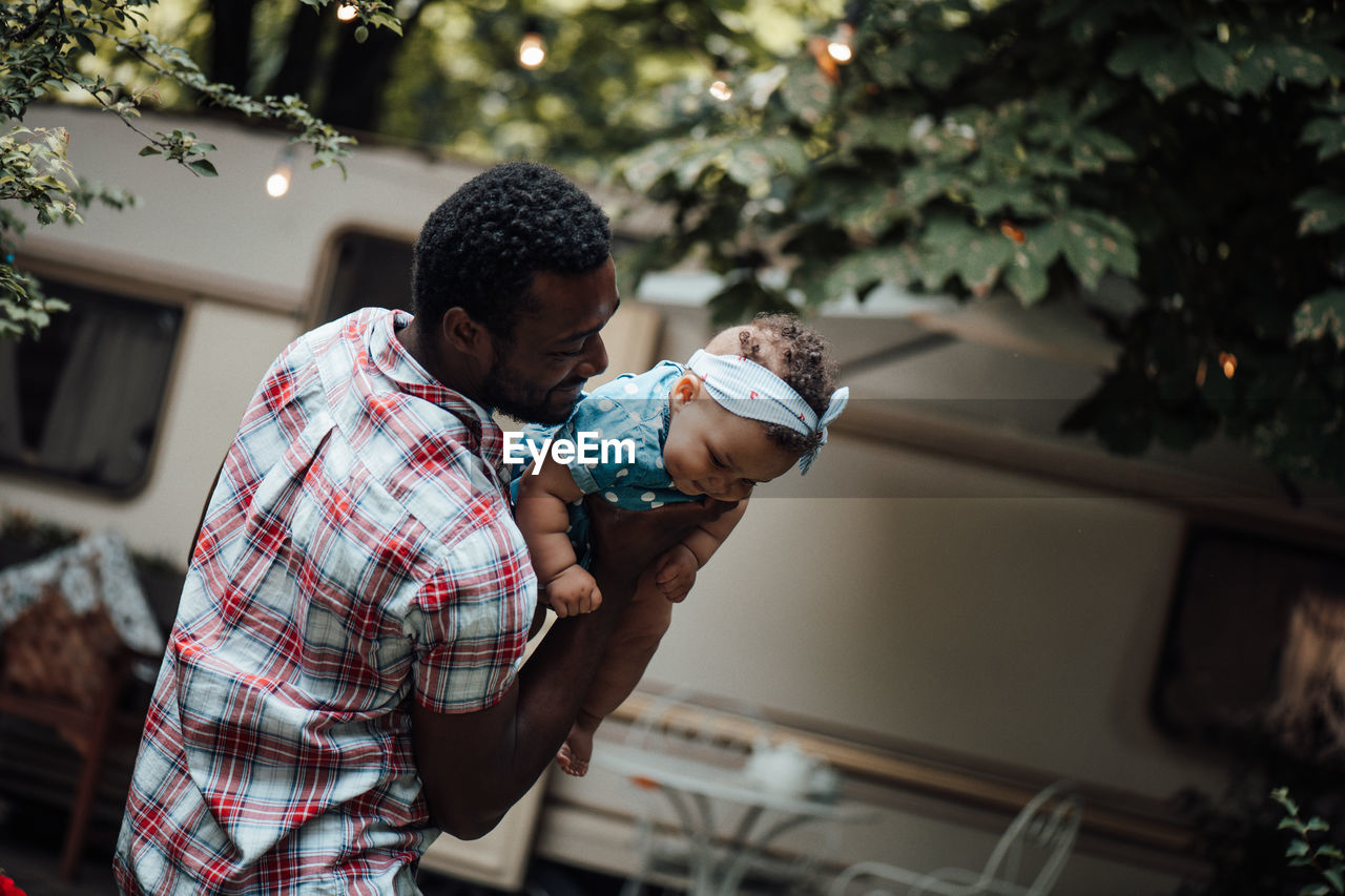 Father carrying daughter on shoulder outdoors