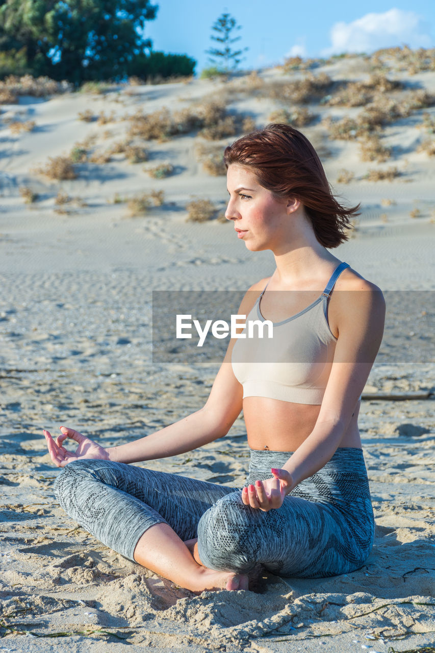 Young woman doing yoga at beach