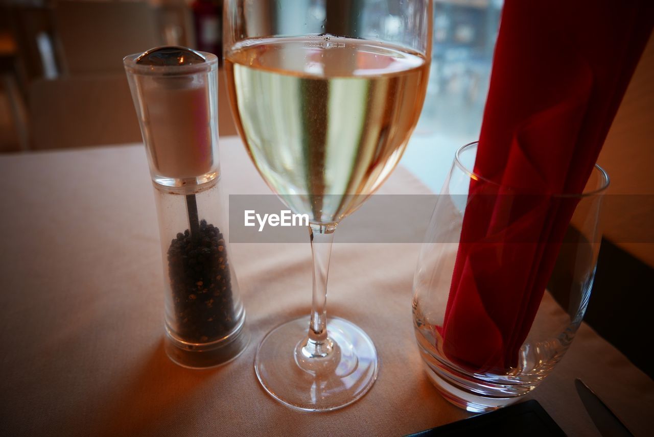 Close-up of white wine and pepper shaker on table in restaurant