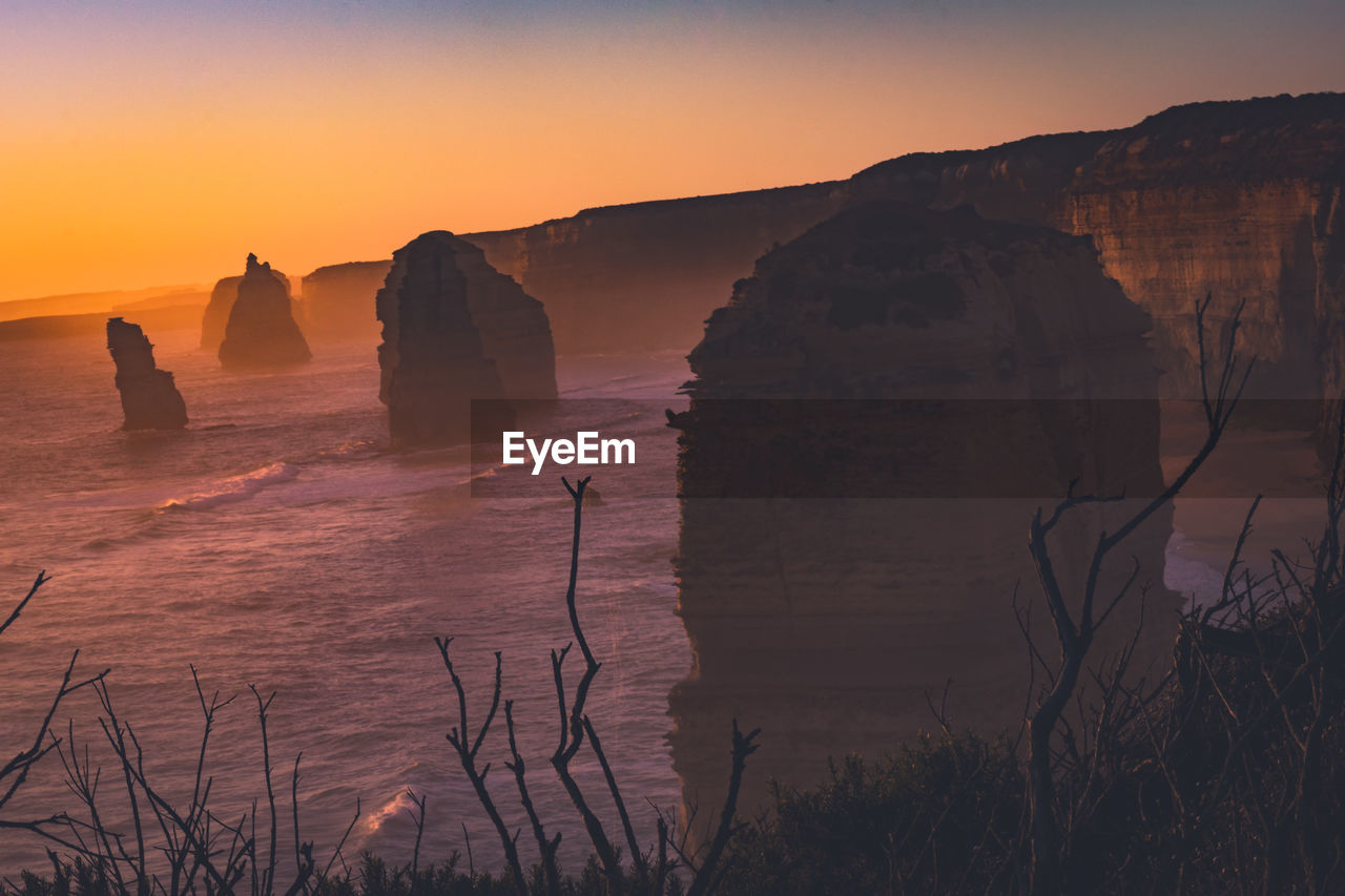 Scenic view of rock formation in sea against sky during sunset