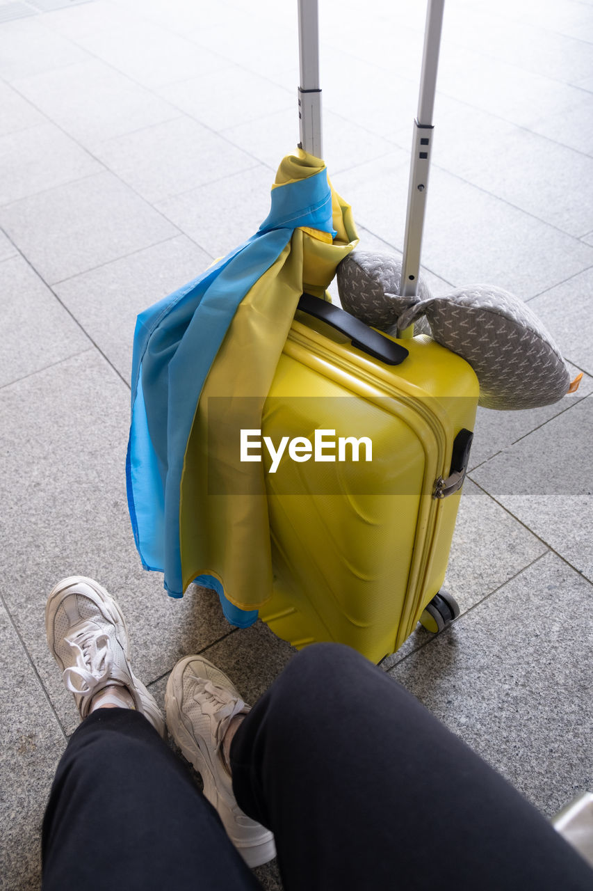yellow, travel, human leg, low section, one person, shoe, flooring, tiled floor, lifestyles, luggage, adult, journey, tile, suitcase, transportation, cleanliness, high angle view, bag, human limb, limb, airport, personal perspective, trip, indoors