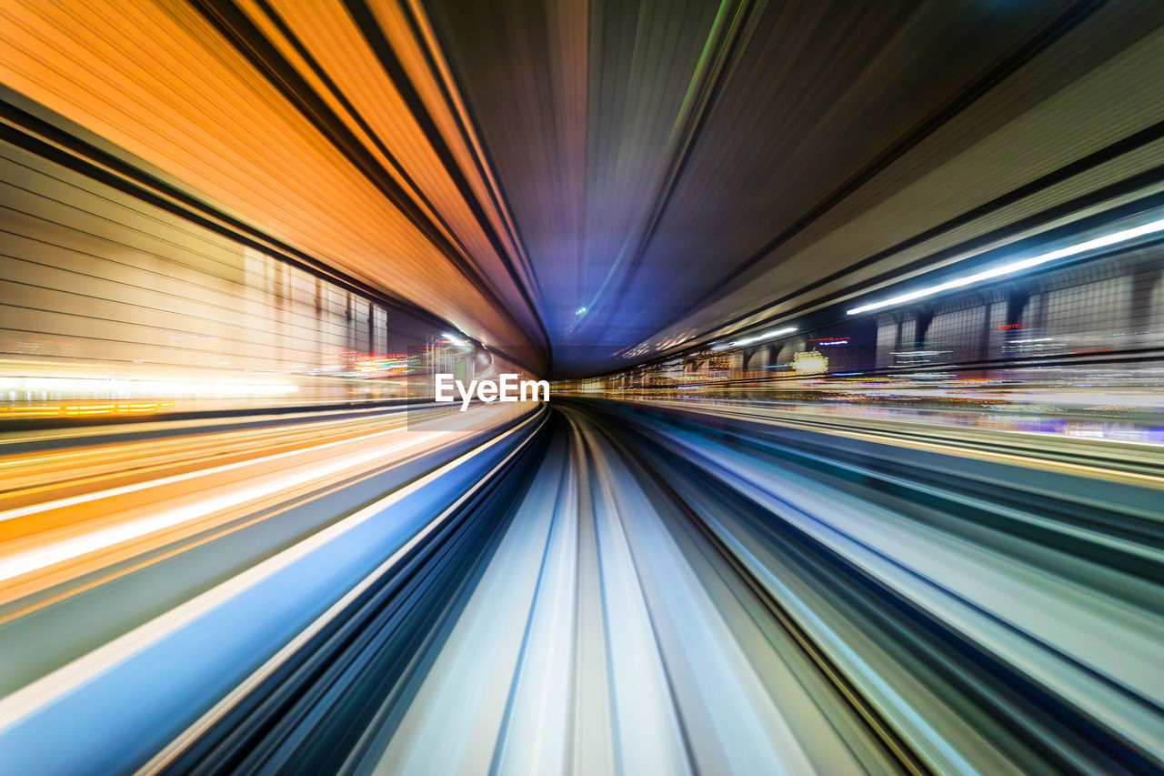 BLURRED MOTION OF LIGHT TRAILS ON ILLUMINATED RAILROAD STATION