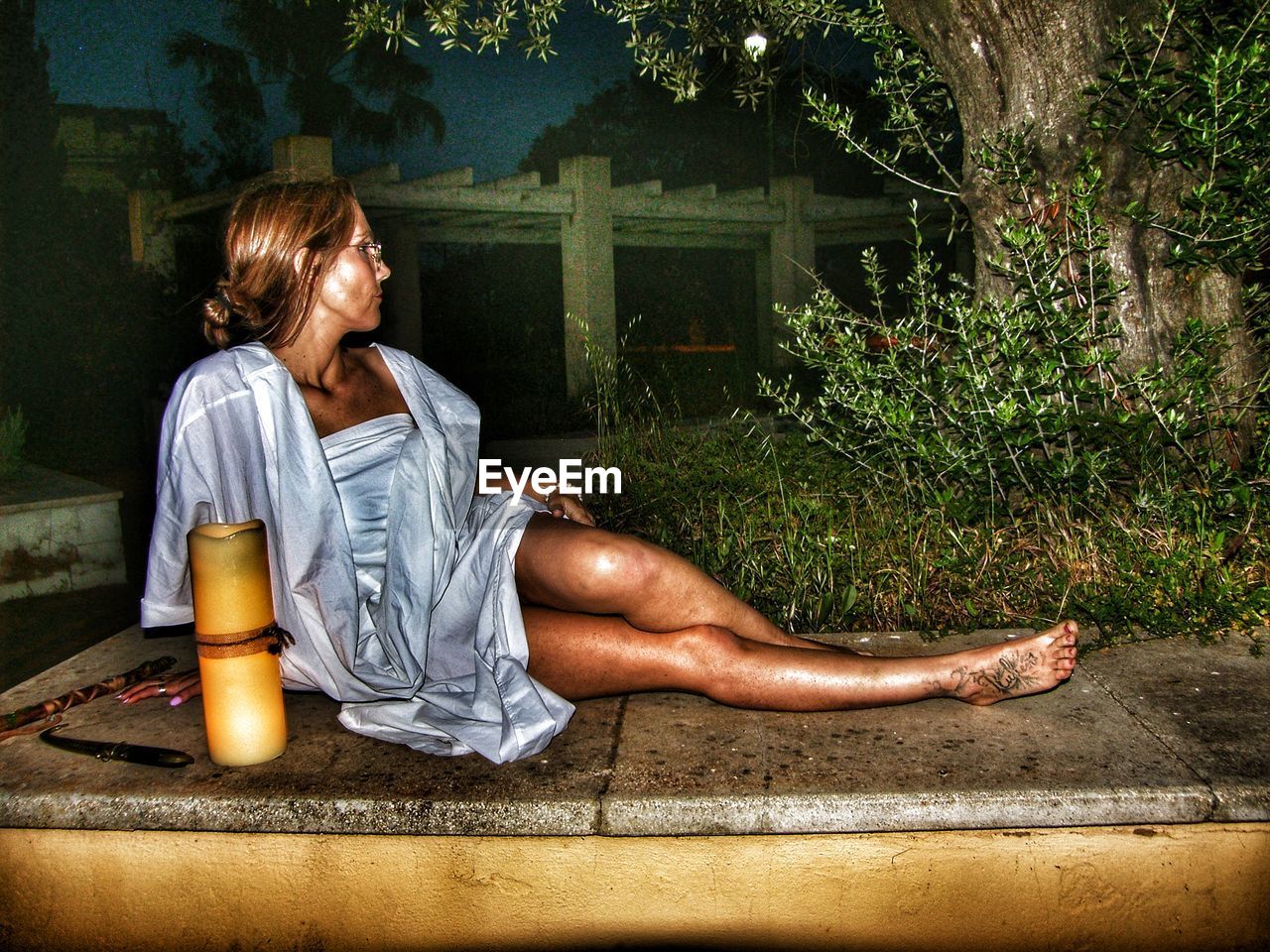 YOUNG WOMAN LOOKING AWAY WHILE SITTING ON SEAT