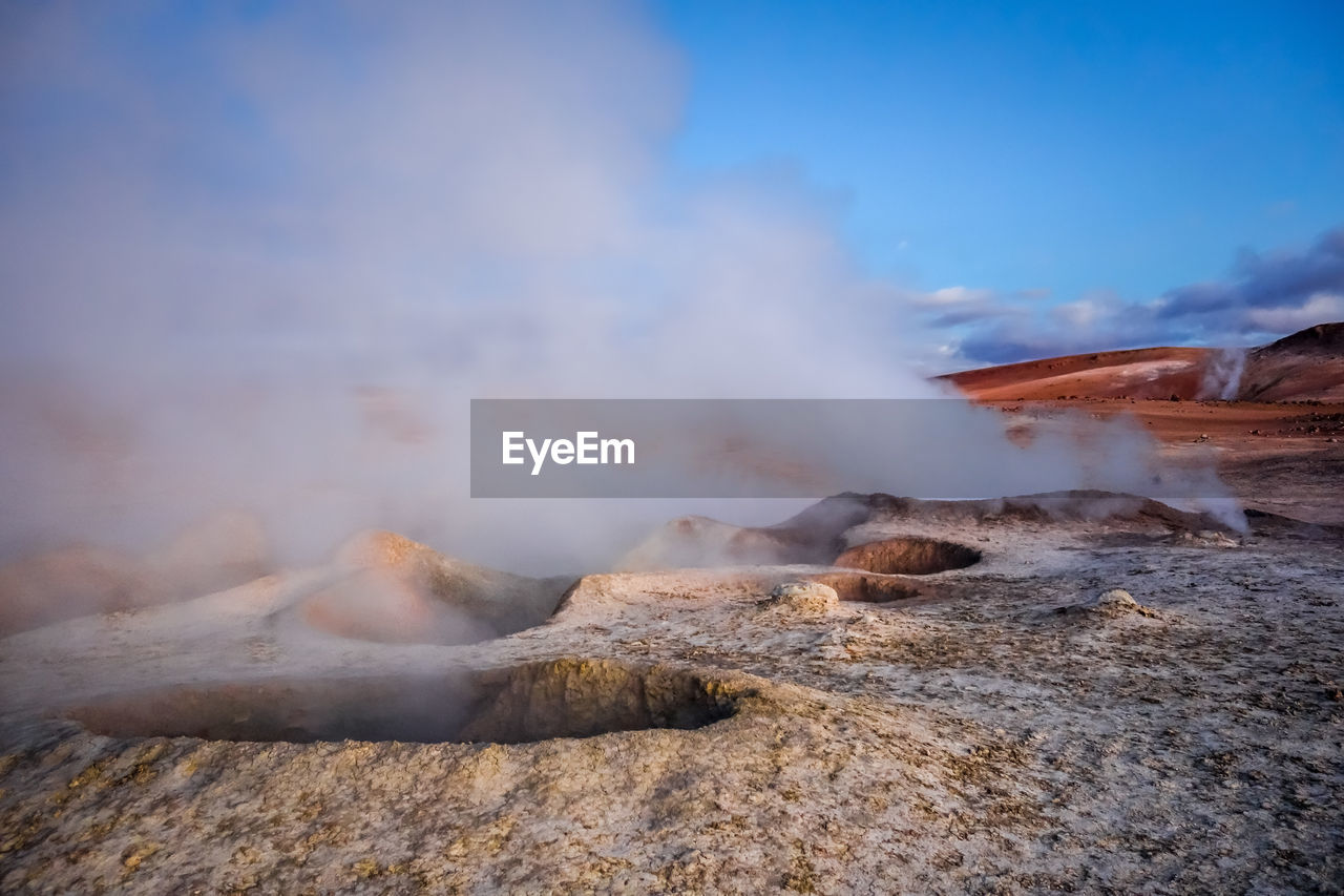 SMOKE EMITTING FROM VOLCANIC LANDSCAPE AGAINST SKY