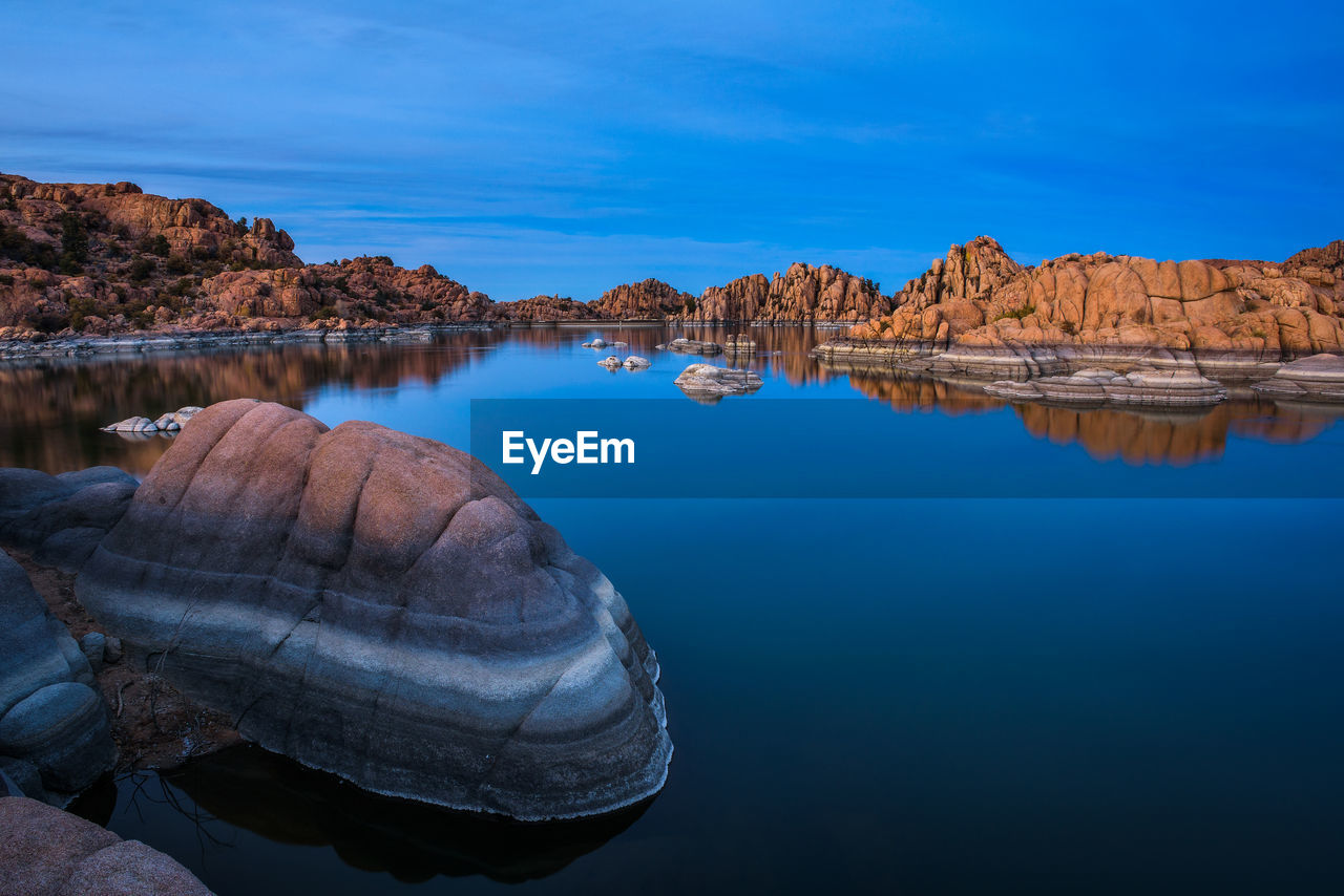 ROCK FORMATION IN LAKE AGAINST BLUE SKY