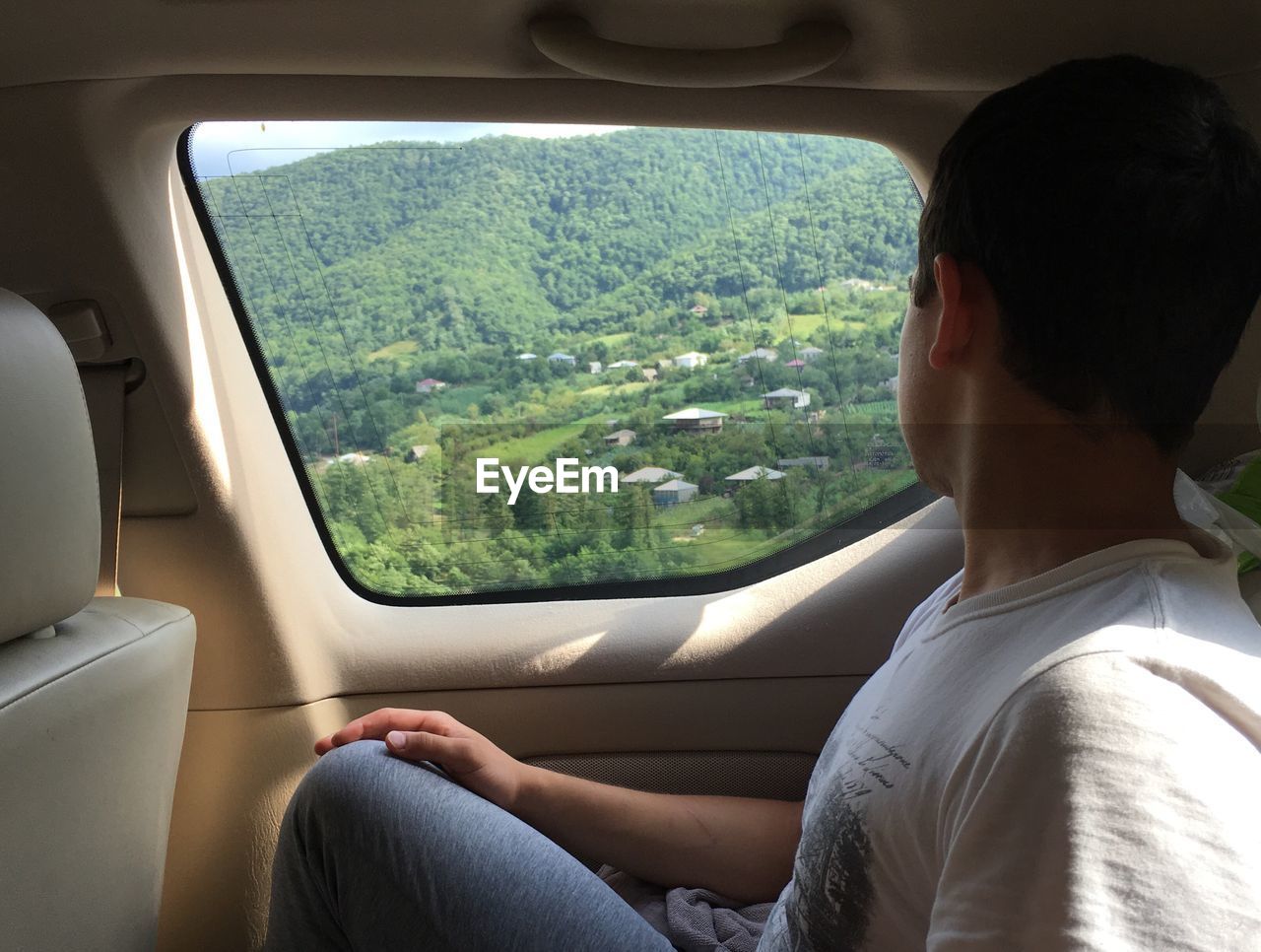 Side view of man looking through window while sitting in car