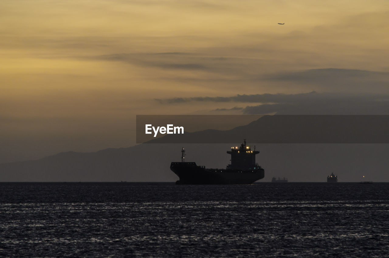 Silhouette ship sailing on sea against sky during sunset