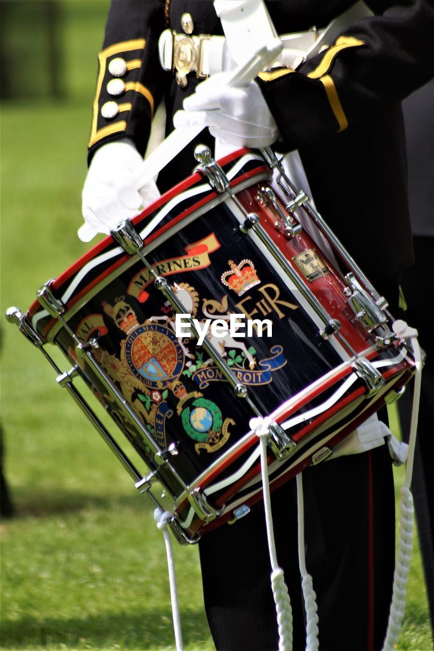 Midsection of man holding drum while standing on field