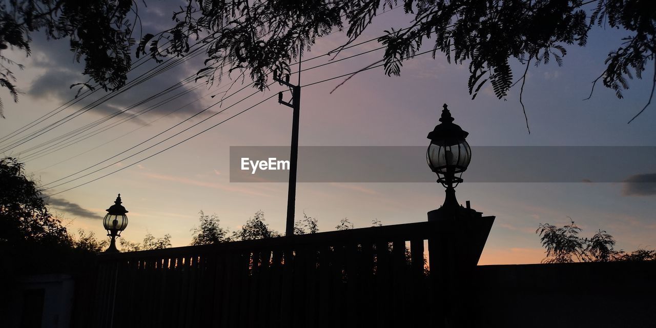 sunset, evening, silhouette, sky, dusk, tree, architecture, nature, darkness, light, plant, street light, cloud, built structure, sunlight, no people, outdoors, lighting equipment, backlighting, lighting, street, building exterior, travel destinations, city