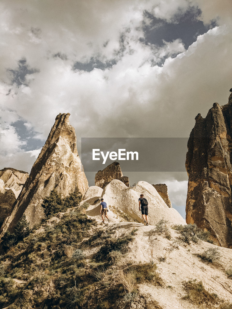 PANORAMIC VIEW OF PEOPLE ON ROCK FORMATION AGAINST SKY