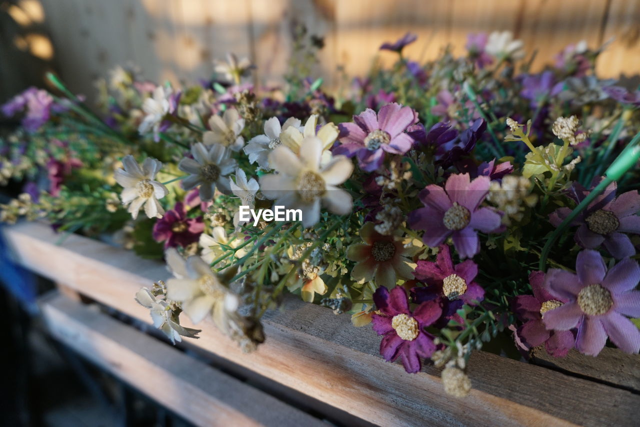 flower, flowering plant, plant, freshness, beauty in nature, floristry, nature, purple, floral design, no people, close-up, bouquet, fragility, arrangement, selective focus, wood, multi colored, flower arrangement, flower head, outdoors, growth, focus on foreground, variation, day, blossom, retail, pink
