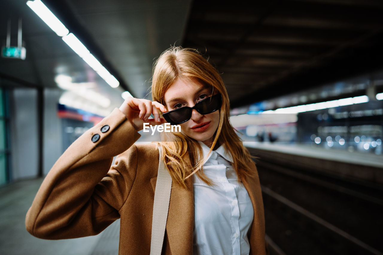 Outdoor portrait of a young beautiful confident woman posing the train station on the background