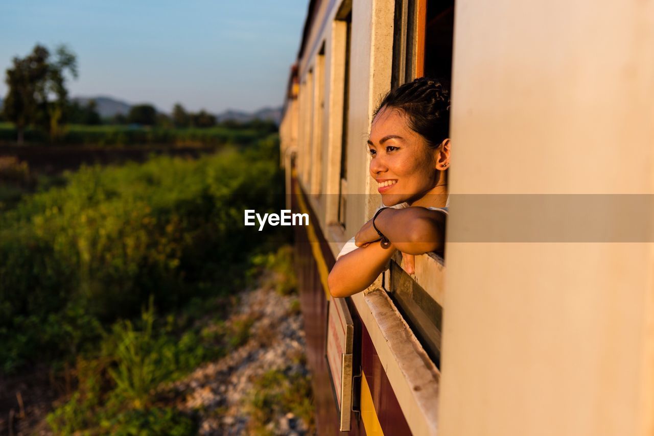 Smiling young woman looking through train window