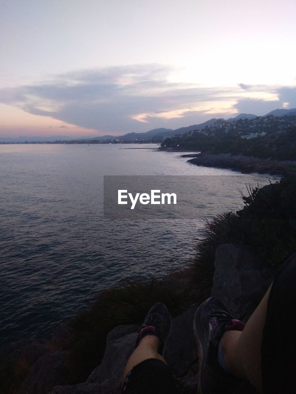 LOW SECTION OF PEOPLE AT SEA SHORE AGAINST SKY